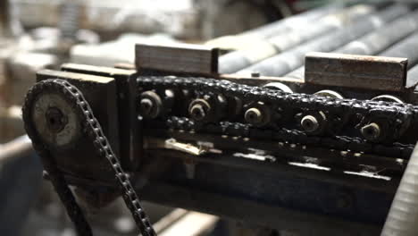 closeup of rotating gears and chains on industry machine conveyor roller