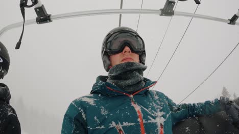 snowboarder riding ski lift in snow up to the top of the mountain at colorado ski resort