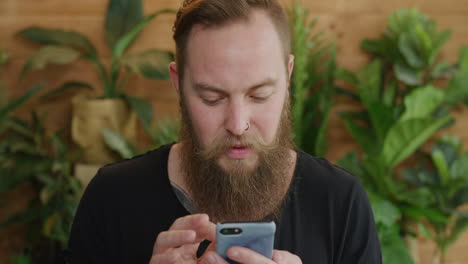 joven caucásico usando un teléfono inteligente retrato de un hipster barbudo navegando en línea buscando pensativo enviando mensajes de texto en el teléfono móvil