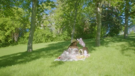 Black-Woman-watching-waiving-smiling-in-park-picnic-blanket