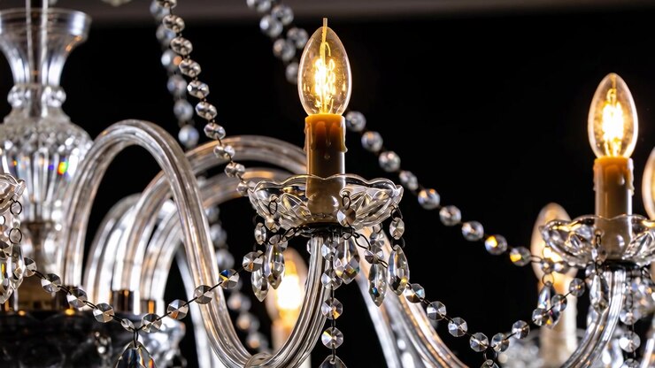 Inquadratura che si allontana rivelando un lampadario di vetro ornato in un atrio poco illuminato, per mostrare bracci e pendenti a goccia.