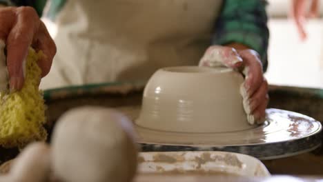 Mid-section-of-female-potter-making-pot