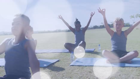 animación de manchas de luz blanca sobre felices escolares diversos haciendo yoga en clase al aire libre