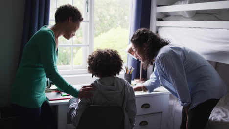 mixed race lesbian couple helping daughter working at a desk