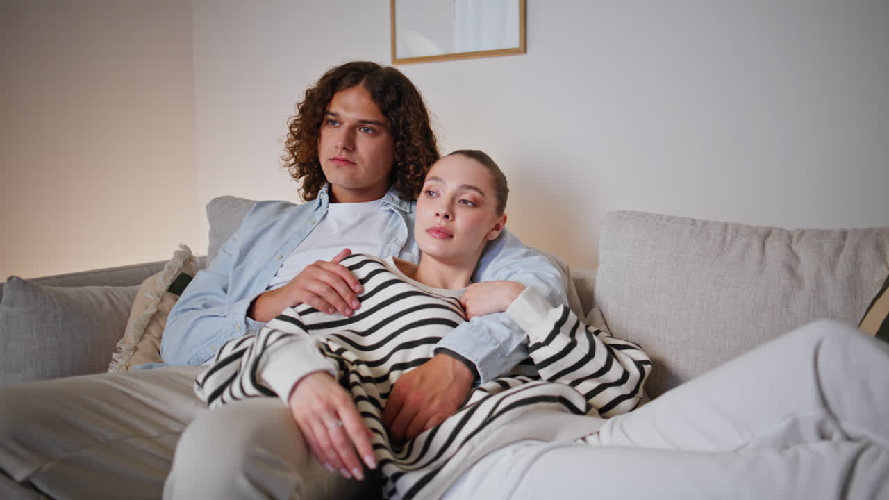 Bonding couple watching TV at comfortable home sofa closeup. Relaxed spouses
