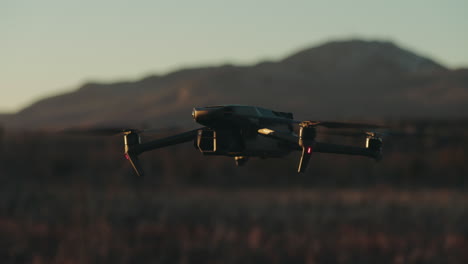 quadcopter moderno flotando sobre campos con fondo de montañas bokeh