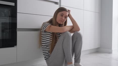 a tired young woman sits on the floor and puts things in boxes