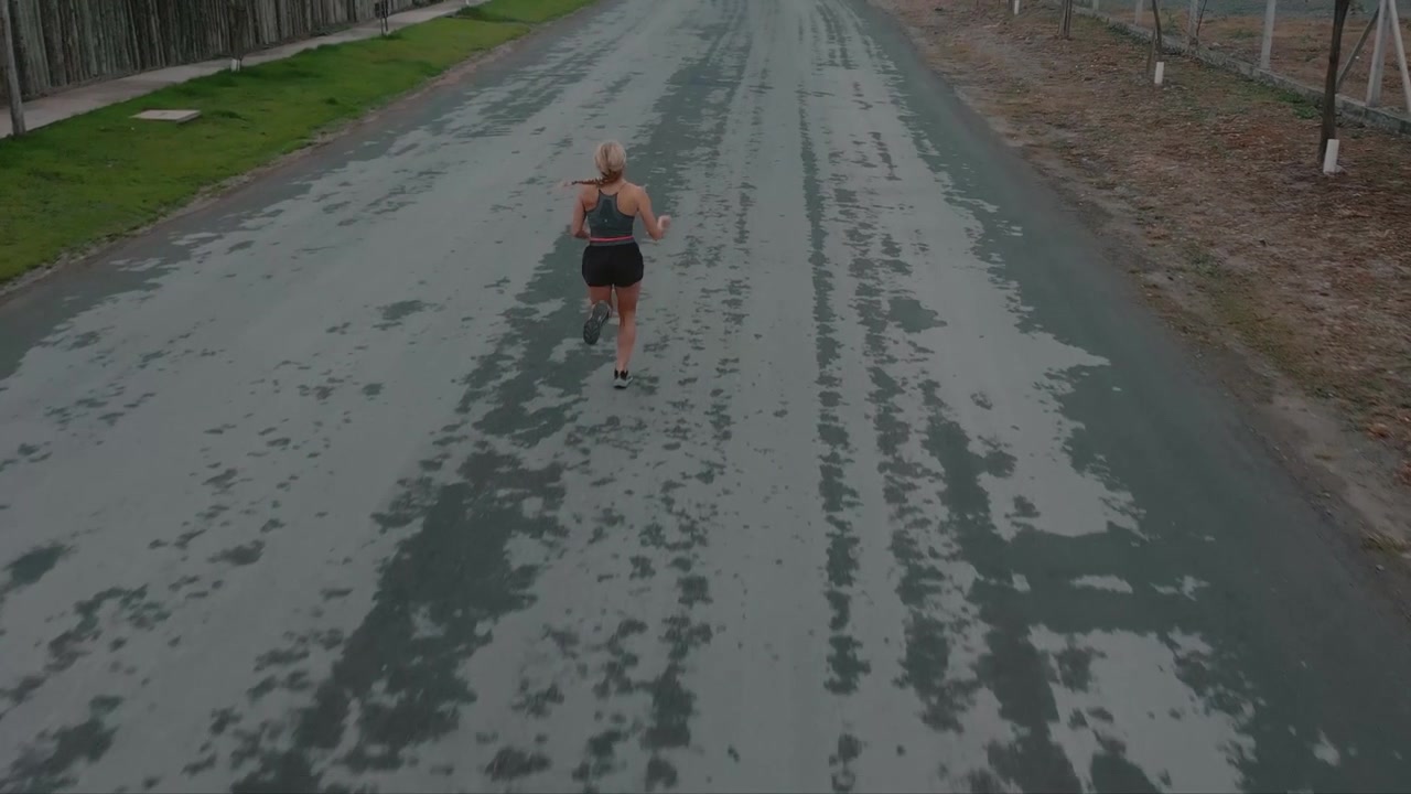 Ung kvinna joggar längs en lugn förortsgata