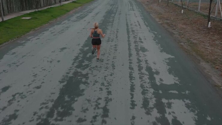 Giovane donna che fa jogging lungo una tranquilla strada suburbana
