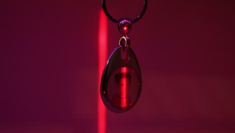 Close-Up-of-the-Hanging-Child's-Photo-in-Metal-Souvenir-Keychain-and-the-Moving-Laser-Light