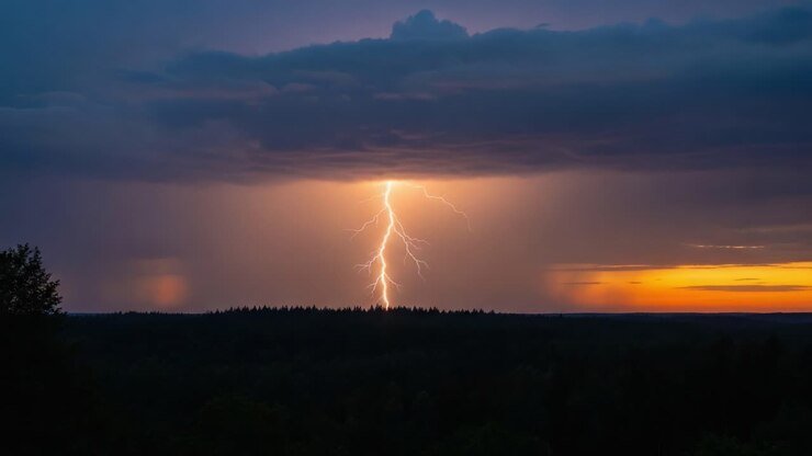 Uno spettacolo mozzafiato della potenza della natura: un brillante fulmine colpisce il paesaggio distante sotto un cielo tempestoso e drammatico al tramonto.