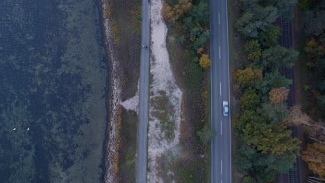 aerial top down shot of driving cars on road and riding bike on coastal lane at hel island, poland