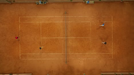 aerial top-down shot of a doubles tennis match being played on a clay court in mendoza