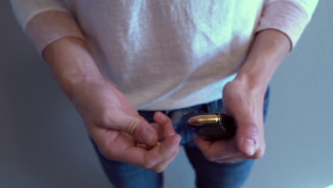 Woman-emptying-bullets-from-handgun-magazine-and-reloading-it