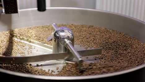 silver drum machine spins and spreads tumbling coffee beans to roast evenly