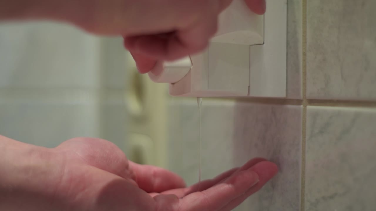 Close up of male hands taking soap out of a soapdispender in the bathroom. Slow motion.