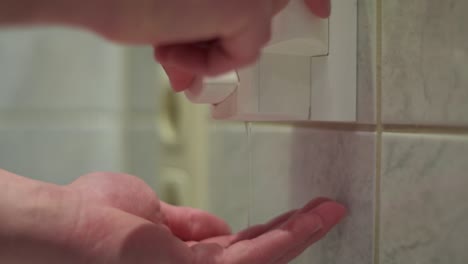close up of male hands taking soap out of a soapdispender in the bathroom. slow motion.