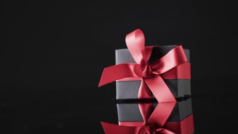 Video-of-gift-box-with-red-ribbon-and-copy-space-over-black-background