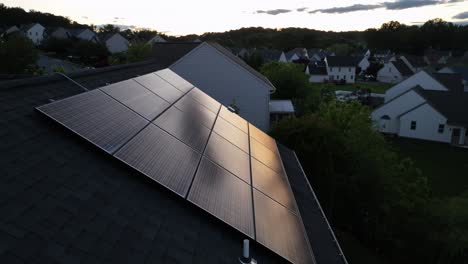 Reflection of golden sunset light on solar panel of house. Aerial tilt up shot. Dusk scene in american housing area located on hills in spring. Quiet scene in noble district. Wide shot.