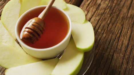 video of honey in jar and apple slices lying on wooden surface