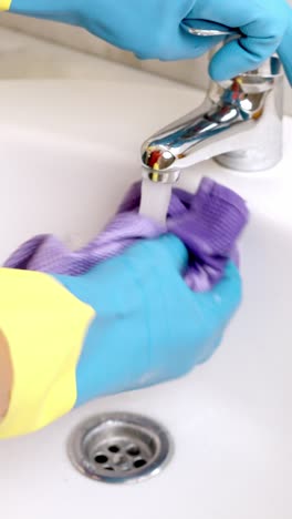 janitor cleaning white sink with purple cloth and yellow gloves