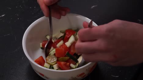 ensaladera fresca y saludable con muchos ingredientes picados aromatizados, verduras añadidas y mezcladas con cucharas