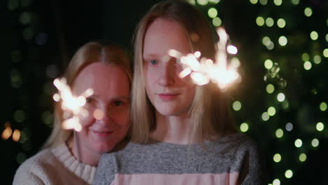 Mom-and-daughter-are-burning-sparklers-on-the-background-of-the-Christmas-tree-at-home