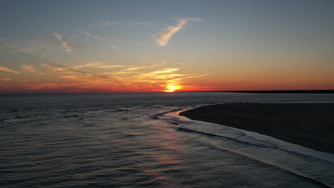 aerial shot of the ocean as the sun is setting over the sea, wide drone shot