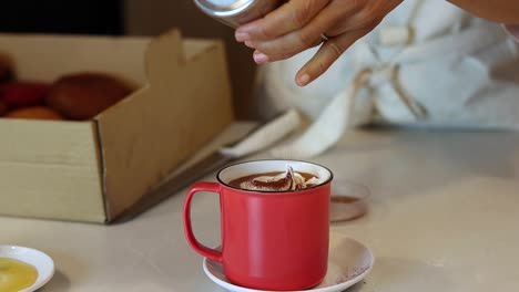 barista de cultivos agregando canela en una taza con bebida de cacao