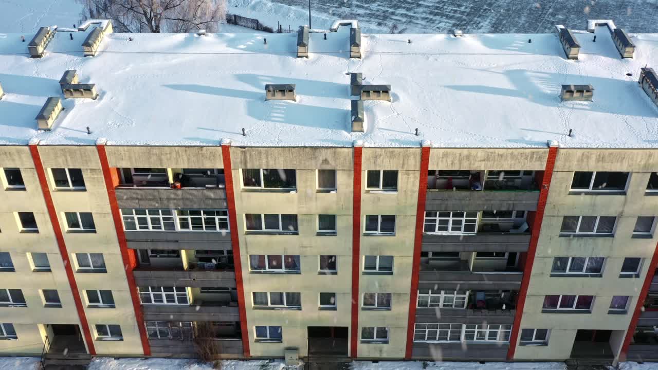 Residential building with snow on its roof and snowfall on sunny morning showing winter environment from above