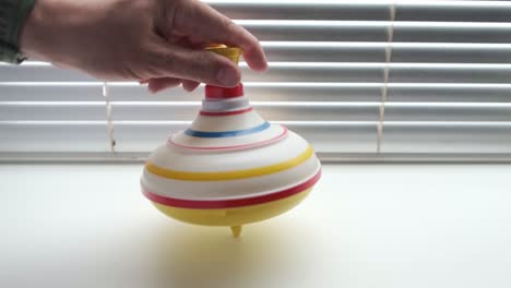 Child toy on background of blinds, untwisted by hand of whirligig.
