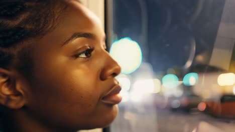 a black woman looking out the window at night