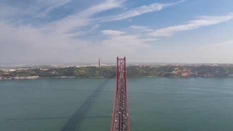 Luftüberschreitung-Des-Verkehrs-über-Die-Brücke-Ponte-25-De-Abril-In-Lissabon-Mit-Dem-Heiligtum-Von-Christus-Dem-König-Im-Hintergrund