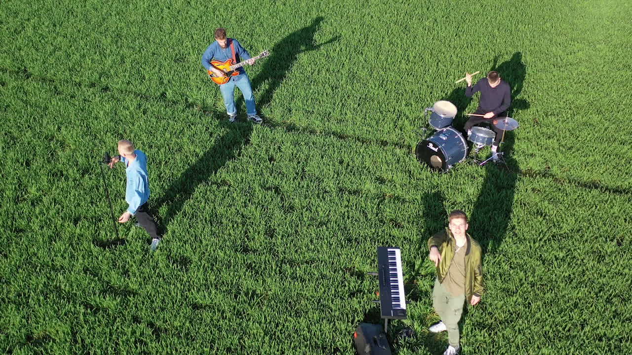 Young men of a music band playing musical instruments. Group of musicians performing music and singing on green field background. Top view.