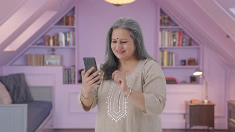 Cheerful-Indian-old-woman-scrolling-through-phone