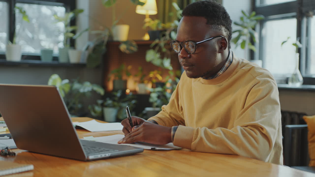 African American Student Using Laptop and Taking Notes as Doing Homework