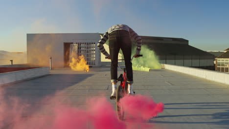 jinete de bmx en un techo saltando y usando granadas de humo