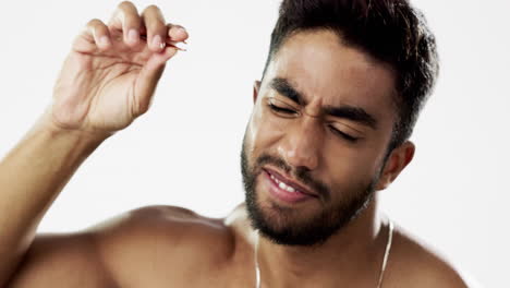 man grooming his eyebrows with a tweezer in studio