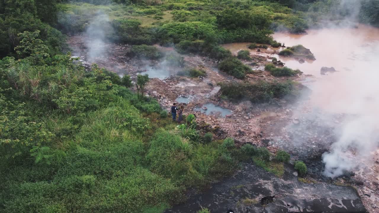 una pareja joven bailando cerca del lago hirviendo.