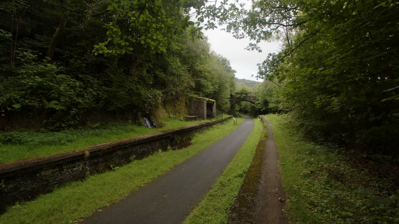 toma extra ancha de la estación de cynonville con el viejo puente ferroviario en el fondo y el sendero para bicicletas
