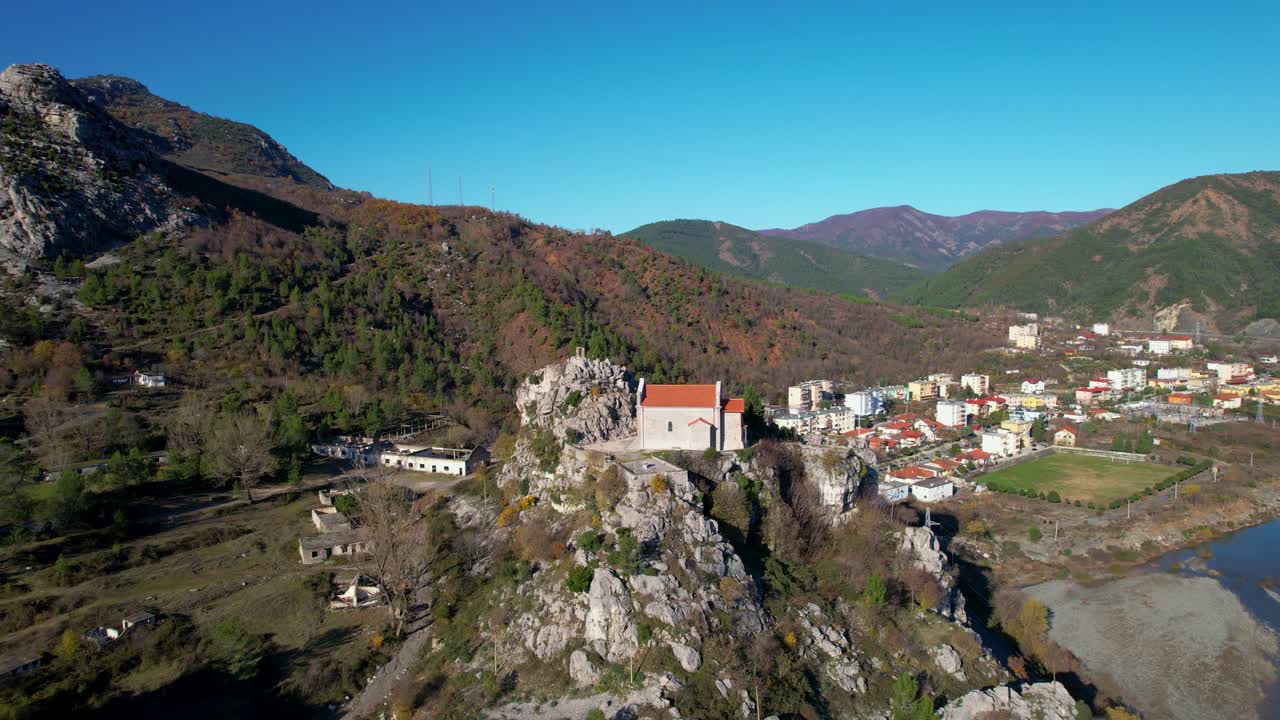 Ancient Monastery Church in Rubik, Albania, Perched on a Rock Alongside the Majestic Mountains and River