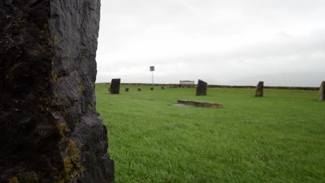 Círculo-De-Piedra-En-Beaumaris-Grass-Promenade-Zona-De-Asientos-Dolly-Izquierda-Revelan-Montañas-Detrás-De-La-Piedra