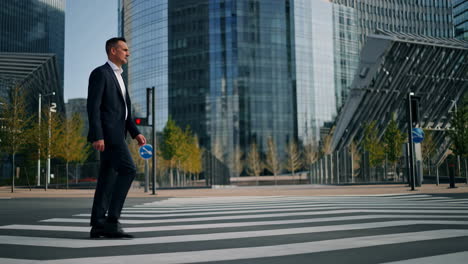 businessman walking across city crosswalk with modern buildings