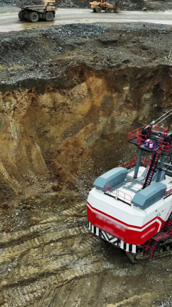 Large Mining Excavator and Heavy Trucks in an Open-Pit Mine