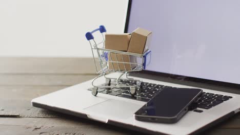 cajas en el carrito de compras y teléfono inteligente en el teclado de la computadora portátil