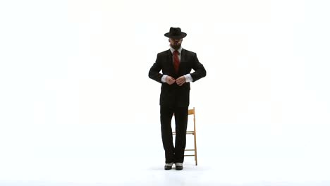 man in suit and hat adjusting tie