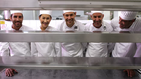 chefs sonrientes de pie en una fila en la estación de orden