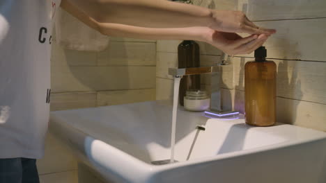 woman opening a modern faucet and washing her hands