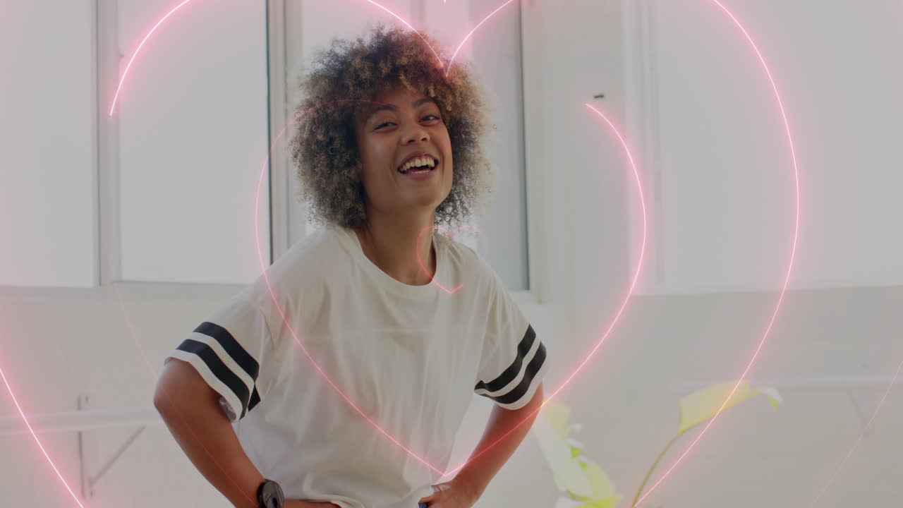 Smiling woman with hands on hips over pink heart animation