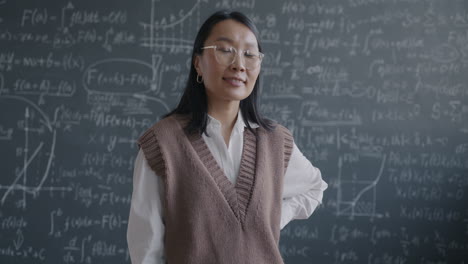 portrait of a teacher in front of a blackboard filled with math equations